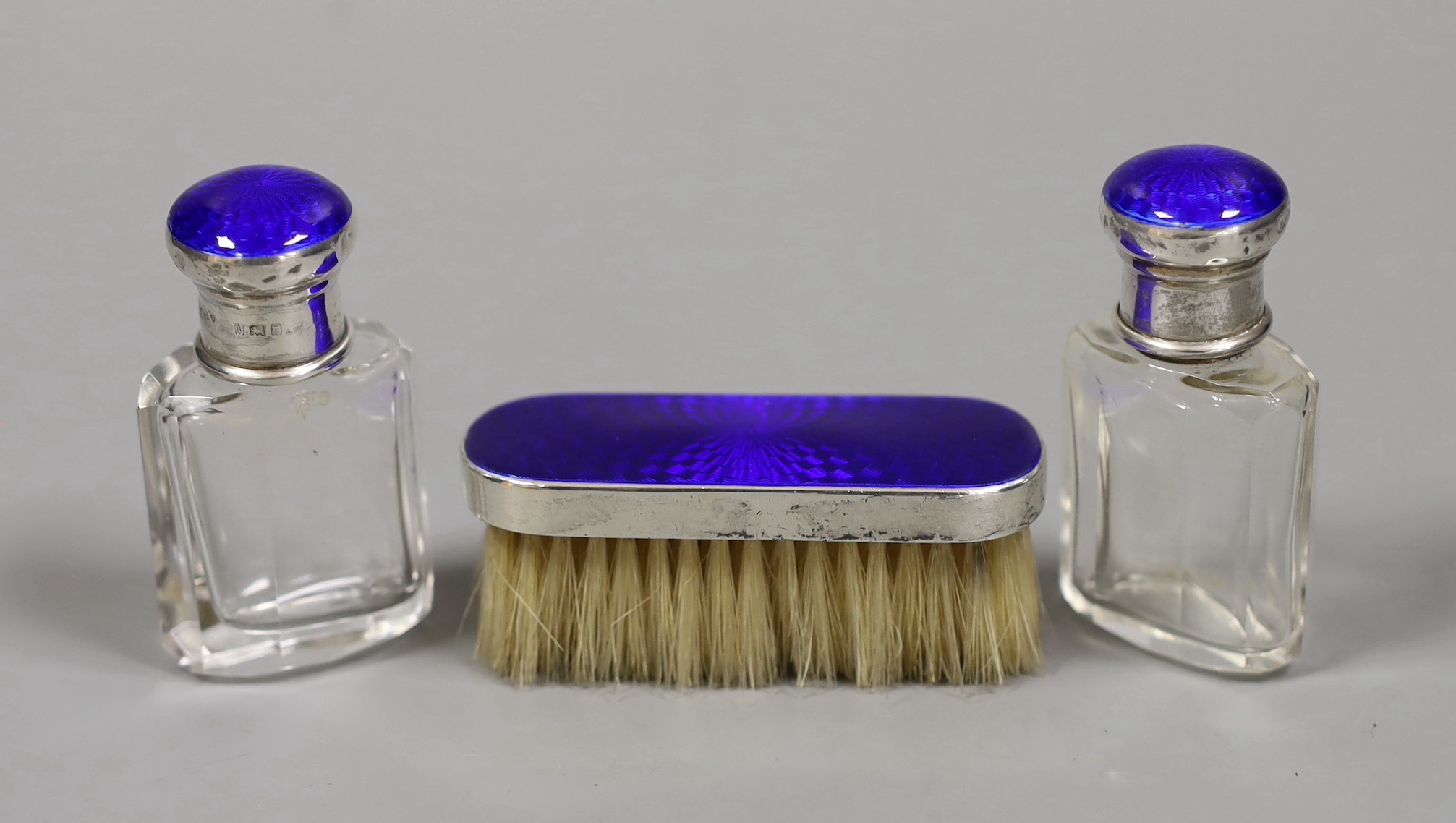 A pair of George V silver and enamel mounted glass scent bottles, 73mm and a small mounted brush, London, 1926.